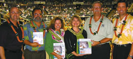 Dawn Groves (with many lei) displays the new phonebook featuring her artwork, surrounded by Hawaiian Telcom and UH Manoa representatives (from left) Mike McHale, Peter Quigley, Denise Konan, David McClain and Mike Ruley. Photo from Moani Wright-Van Alst.