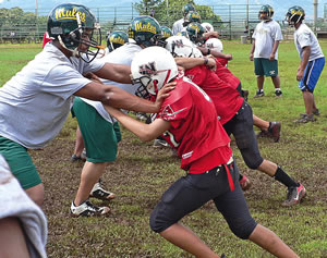 Leilehua players show the Wahiawa Thunderbolts how to get it done on defense during a training camp power drill: “Stay low and fire out with low pad level while shooting the hands and moving your feet.” Photo from Michelle Jenks.