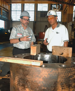 Chief engineer Brian Yim (right) shows engineering professor Ronald Knapp how a propeller shaft connector is refurbished at the Inside Machining Shop at Pearl Harbor Shipyard. Knapp heads the mechanical engineering department at UH-Manoa.
