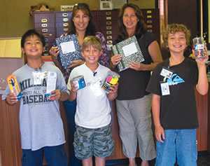 Mililani Waena fourth-graders (from left) Geoffrey Moore, Bradley Patterson and Nathanielle Steele (with adults Samantha Spain and Krysti Peacock in back) show off their new supplies from the drive. Photo from Krysti Peacock.