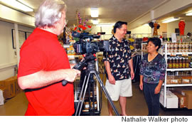 John Noland sets up a shot for a commercial with Susan Morita from Menehune Mac Chocolate Factory. Videographer is Chris Rust.