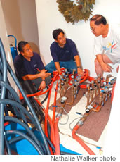 From left, Pacific Pipe Restoration lead technician Romeo Penafiel and owner John Nakamura show homeowner Chris Jay how they cycle airflow during the pipe-cleaning process