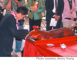 Keith Lim cuts a piece of the pig for the offering