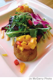 Kalakaua Crab Cakes are sauteed and then served with roasted red pepper sauce and tropical mango salsa