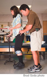 Therapist Nelson Oshiro works with patient Louise Liu, who is wearing a FES device