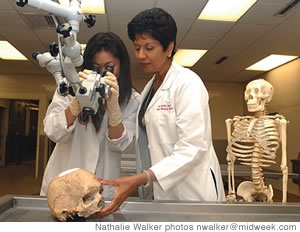 Dr. Kanthi De Alwis and Dr. Gayle Suzuki examine a skull with a gunshot wound