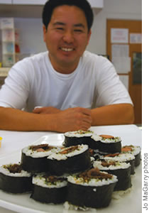 Owner Arrison Iwahiro with the most recent addition to the deli menu -'rolls' filled with hot dogs, teri beef and vegetables.