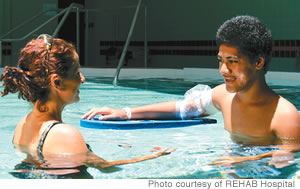 Aphysical therapist works on balance and coordination with a patient in REHAB's therapy pool