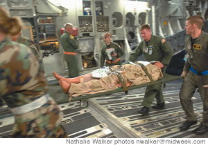 Air Force emergency personnel carry a victim aboard a C-17 for evacuation