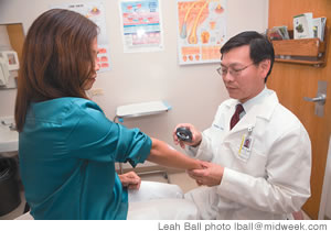 Dr. Bradley Lau checks a patient's arm with the dermascope