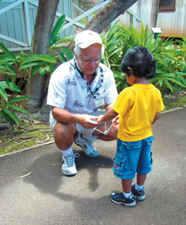 Hawaii’s Plantation Village volunteer Gary Tokuda shows a visiting boy how to play the buzz saw. The village is gearing up for a day of fun for the keiki on Oct. 7. Photo by Sandi Yara.