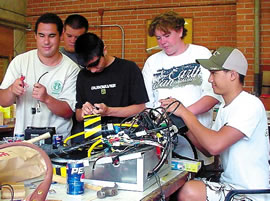 Students Keoni Hall (left), Zach Fischer, Trevor Johnson, Nate Franco and Jacob Pantastico fiddle with ‘Hammerhead’ before taking it to a national robotics contest. Photo by David Izumi.