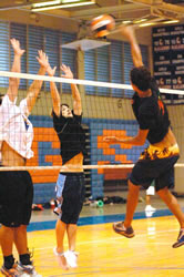 Tyler Caswell and Pono Wong go up for a block against former Kalaheo volleyball star Chris Hatori. According to the team, Kalaheo alumni often turn out to play against them at practices. Photo by Nathalie Walker, staff photographer.