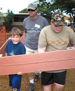 Dax Mench and Steve and Nicholas Seifried carry a freshly minted planter which will grace (Jack and Kim Johnson’s) Kokua Hawaii Foundation’s organic garden project at Aikahi Elementary School. Photo by Byron Lee, staff photographer.