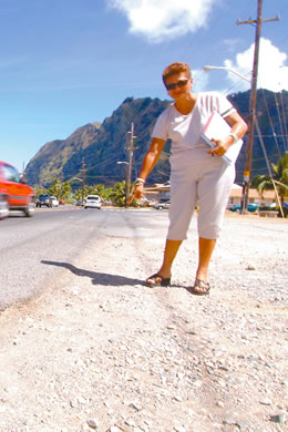 Blanche McMillan points out pukas in the mauka shoulder of Kalanianaole Highway between Nakini and Oluolu streets, which she says is hazardous travel for pedestrians young and old. Repairs are months away, according to state highway officials. Photo by Nathalie Walker, staff photographer.