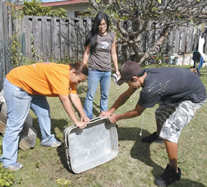 Kalaheo High students Meigan Christopher, Rochelle Nicholson and Chris Ciervo clean up the back yard Feb. 10 at the Family Promise day center. Photo by Byron Lee