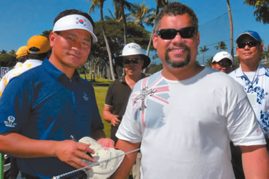 2008 Sony Open in Hawaii champion KJ Choi signs a hat for golf fan Kaleo Tafao of Kalihi.