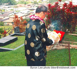 Lawrence Siu burning offerings of spiritual paper money and a eulogy to the ancestors