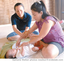 Aoi Wright shows Dayna Hagihara how much pressure to use when massaging her baby, Jordan Ahn-Nicholson