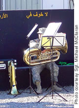 Sgt. Quincy Dunker and his tuba at a memorial wall in Iraq