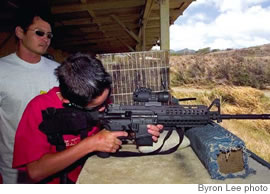 Thomas Chow watches Spencer Young, 12, shoot for the first time