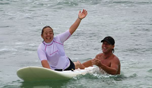 Kayla Adams goes surfing with the help of Mark Marble (right) and his AccesSurf program. Photo courtesy of AccesSurf Hawaii.